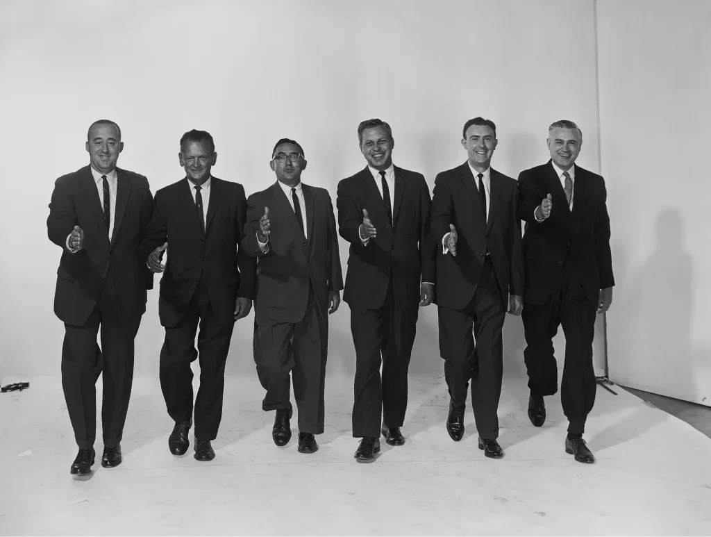 Six men in suits walking towards the camera