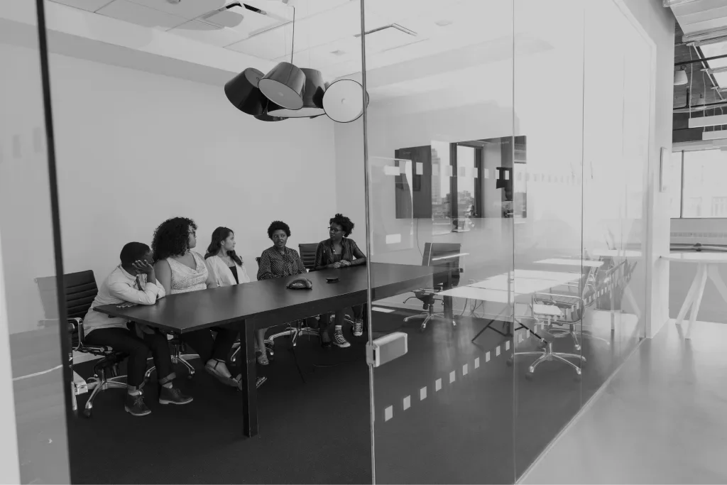 People around a table in a glass meeting room
