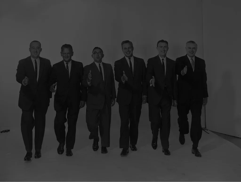 Six men in suits walking towards the camera